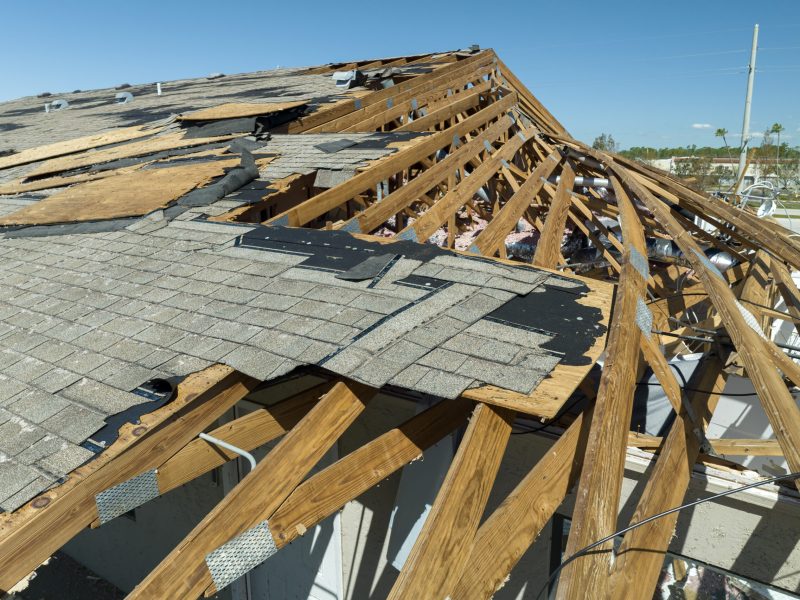 Damaged house roof with missing shingles after hurricane Ian in Florida. Consequences of natural disaster.